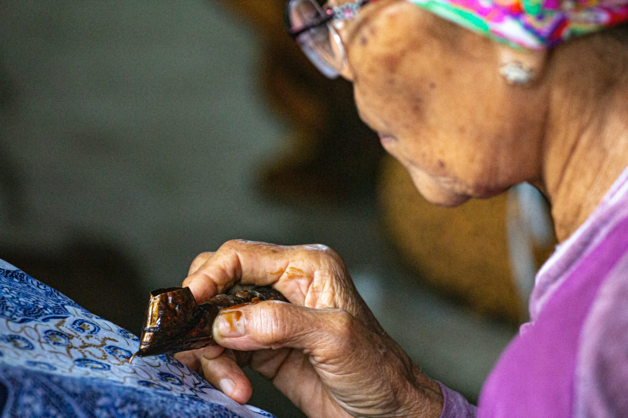 An Indonesian batik artist hand draws a motif using the canting (batik pen). 