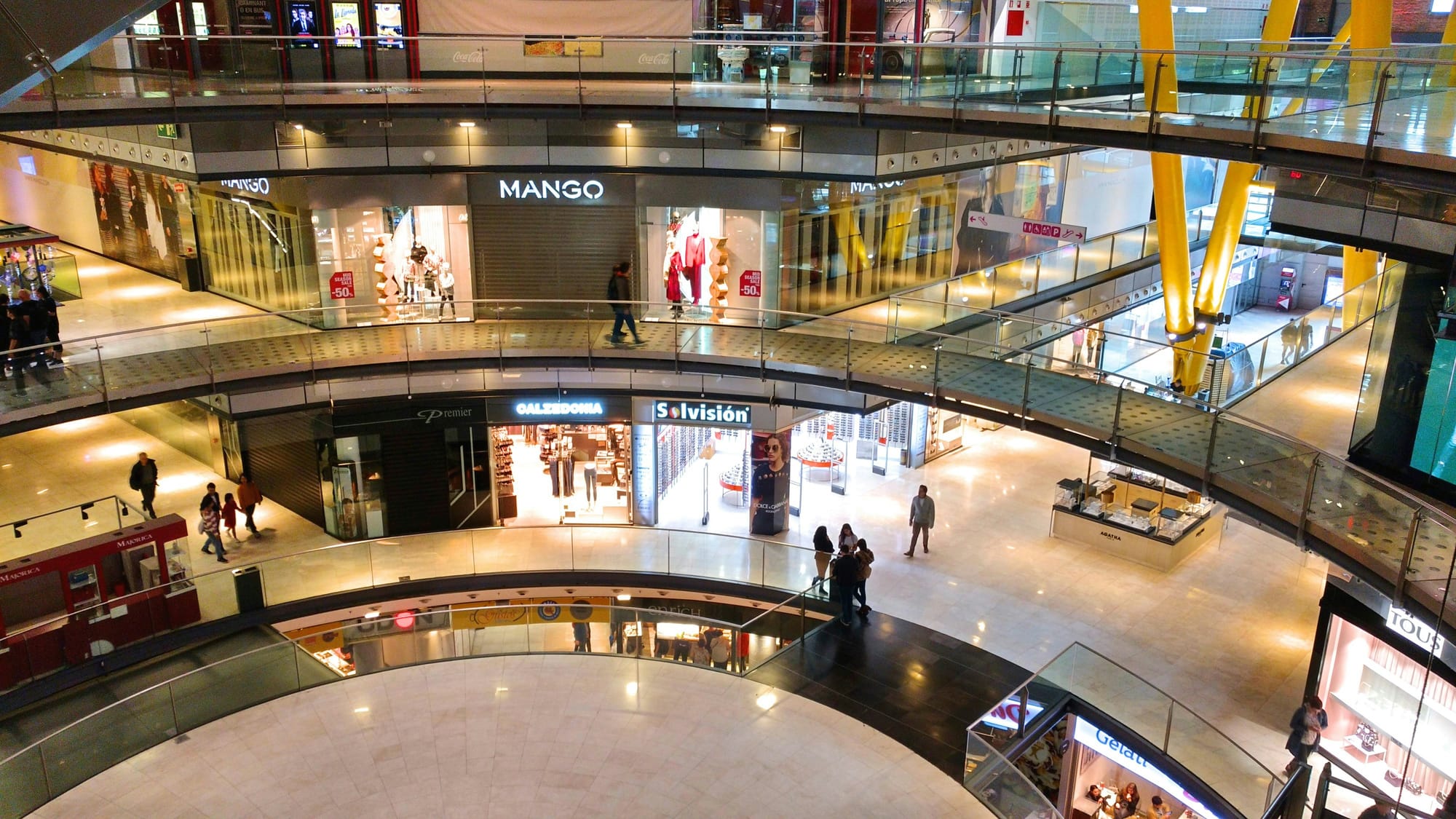 A large, modern multi-level shopping mall with recognizable brand name outlets
